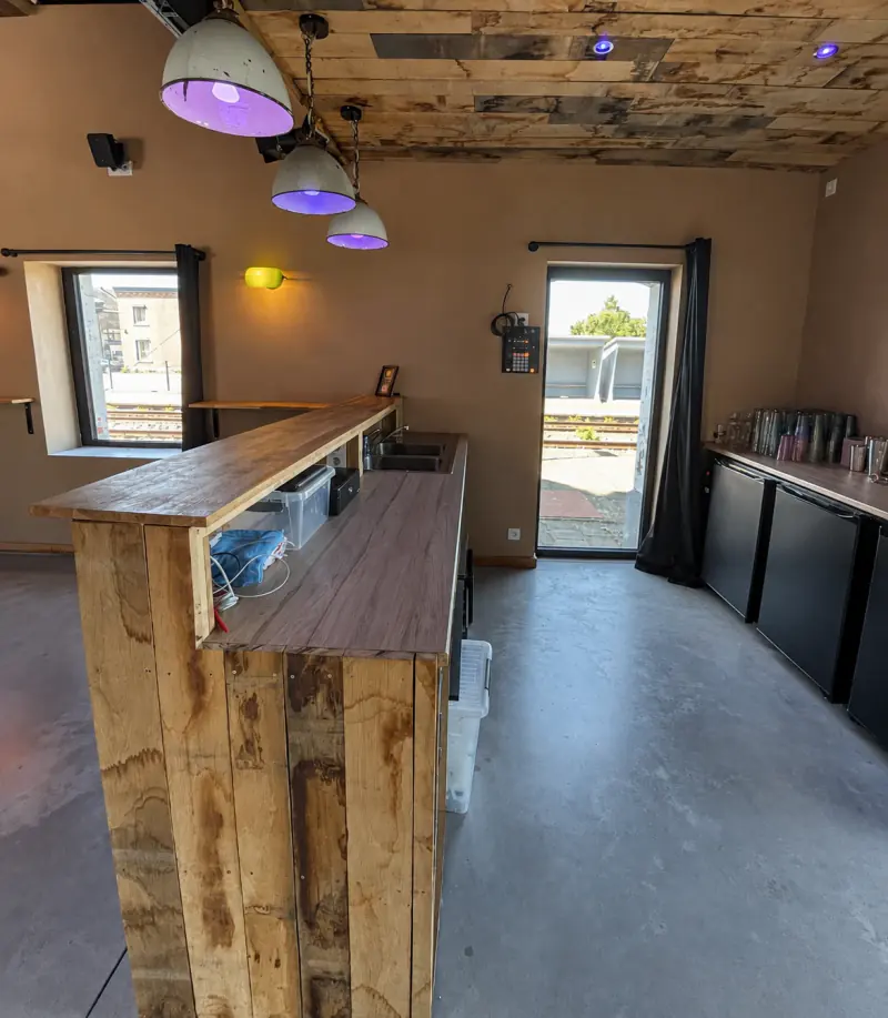 Le bar avec comptoir en bois, évier, réfrigérateurs et verrerie