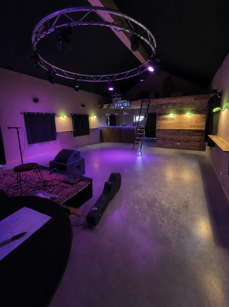 La salle vide en soirée, avec le bar, la scène et l’éclairage violet